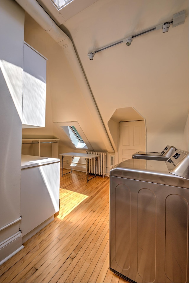 clothes washing area featuring a skylight, separate washer and dryer, and light wood-type flooring