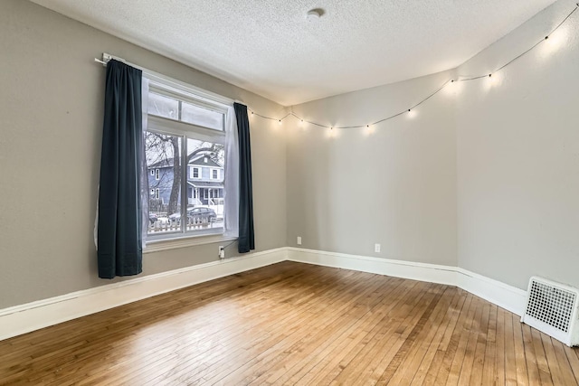 empty room featuring wood-type flooring and a textured ceiling