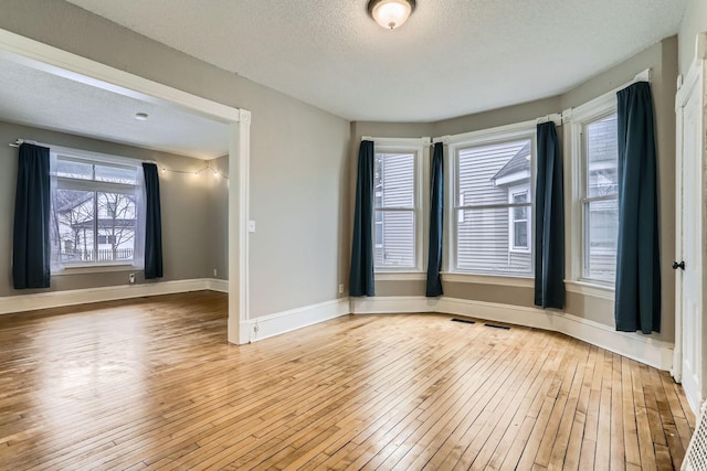 spare room with light hardwood / wood-style floors and a textured ceiling