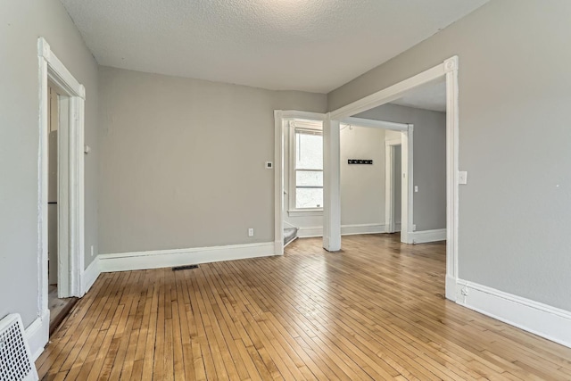 spare room featuring a textured ceiling and light hardwood / wood-style flooring