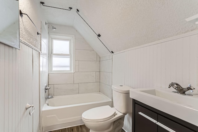 full bathroom featuring lofted ceiling, toilet, tiled shower / bath, a textured ceiling, and vanity