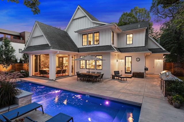 back house at dusk featuring a fenced in pool and a patio