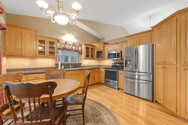 kitchen with sink, light hardwood / wood-style flooring, appliances with stainless steel finishes, vaulted ceiling, and a chandelier