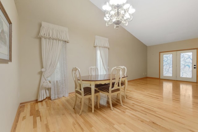 dining space featuring high vaulted ceiling, light hardwood / wood-style floors, french doors, and a chandelier