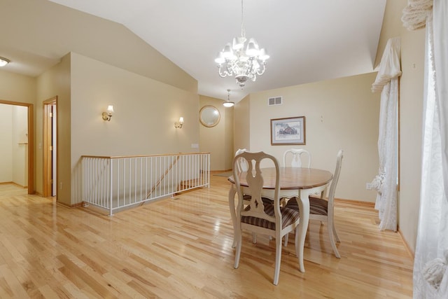 dining area featuring an inviting chandelier, lofted ceiling, and light wood-type flooring