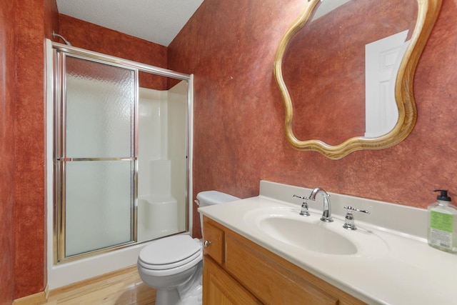 bathroom featuring hardwood / wood-style floors, vanity, walk in shower, toilet, and a textured ceiling