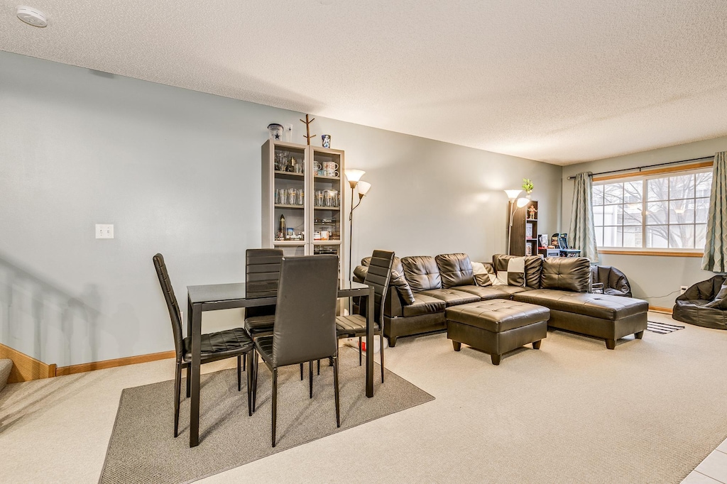 living area with a textured ceiling, baseboards, and carpet flooring