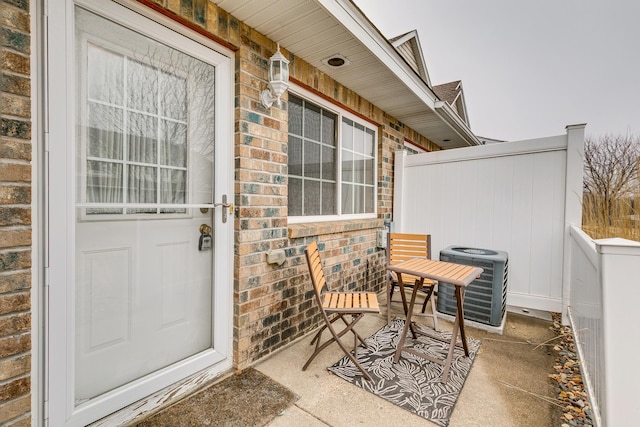 entrance to property with cooling unit, brick siding, and fence