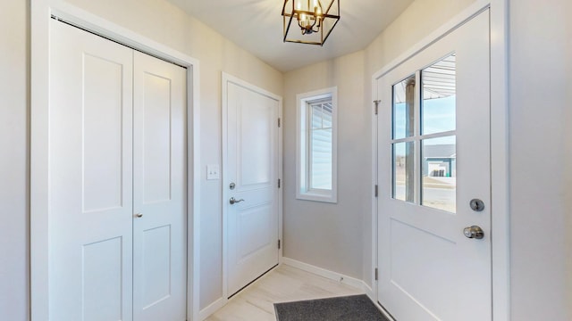 doorway to outside featuring a notable chandelier and baseboards