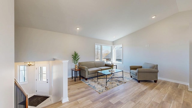 living area with an inviting chandelier, lofted ceiling, recessed lighting, and light wood finished floors