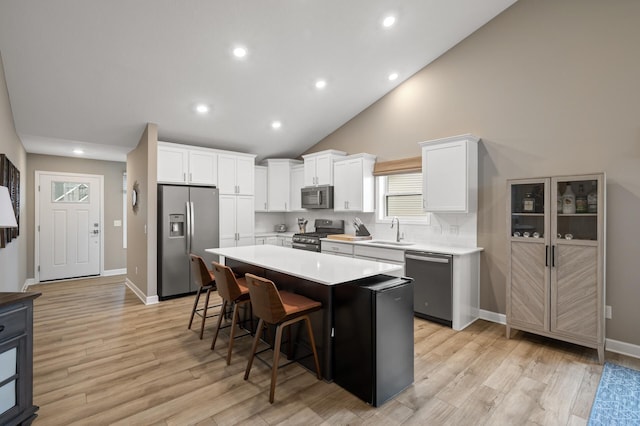 kitchen with white cabinets, appliances with stainless steel finishes, a breakfast bar, a center island, and a sink