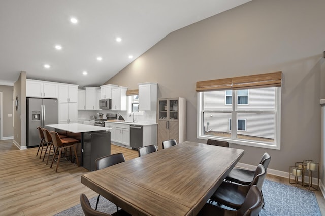 dining space with high vaulted ceiling, recessed lighting, light wood-style flooring, and baseboards