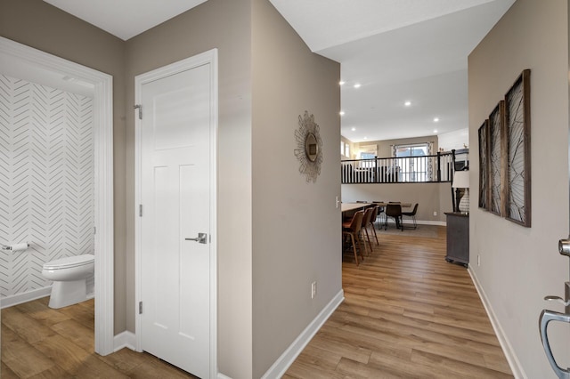 corridor with light wood-type flooring, baseboards, and recessed lighting