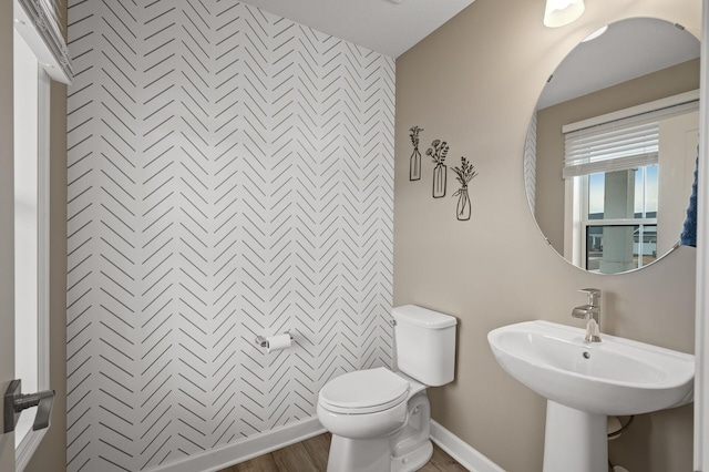 bathroom with an accent wall, baseboards, a sink, and toilet