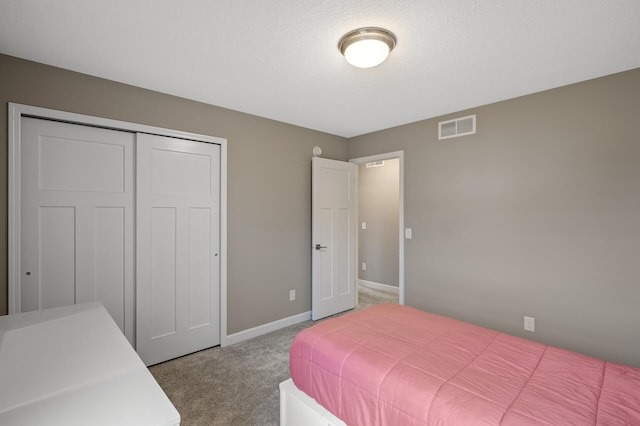 bedroom with baseboards, visible vents, a textured ceiling, carpet floors, and a closet