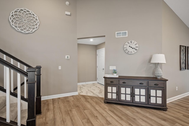 foyer with stairs, wood finished floors, visible vents, and baseboards