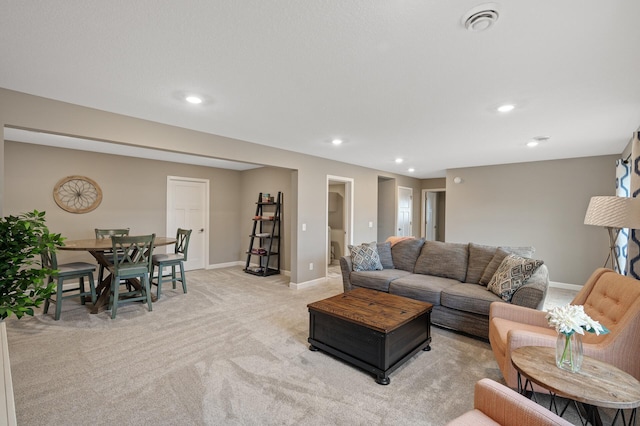 living area with recessed lighting, light colored carpet, visible vents, and baseboards