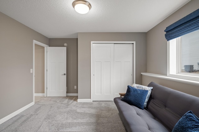 living area with a textured ceiling, baseboards, and carpet flooring