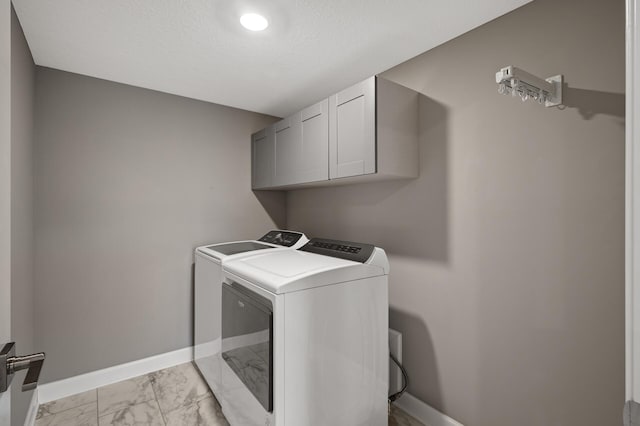 washroom with cabinet space, baseboards, marble finish floor, a textured ceiling, and washing machine and dryer