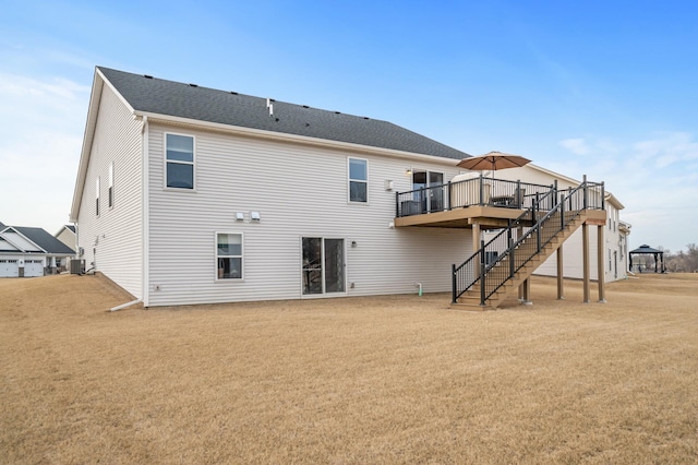 rear view of property with a shingled roof, a lawn, stairway, central AC, and a wooden deck