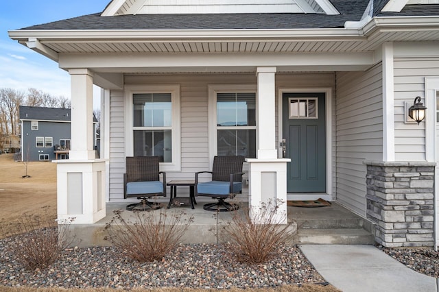 doorway to property featuring a shingled roof and covered porch