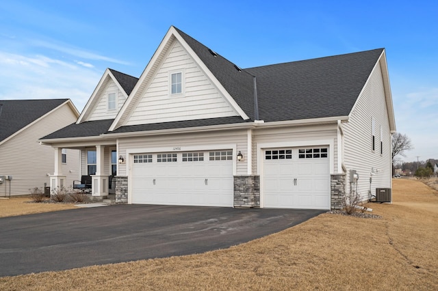 view of front of property with a garage, stone siding, a shingled roof, and aphalt driveway