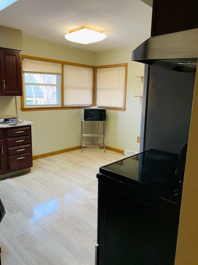 kitchen featuring black range with electric stovetop, dark brown cabinets, and light wood-type flooring