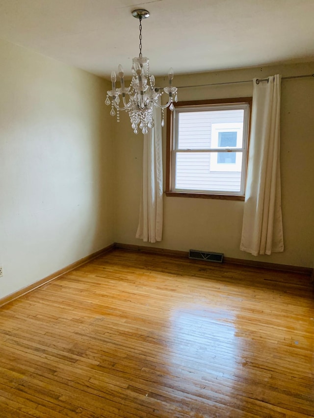 empty room featuring a chandelier and light hardwood / wood-style flooring