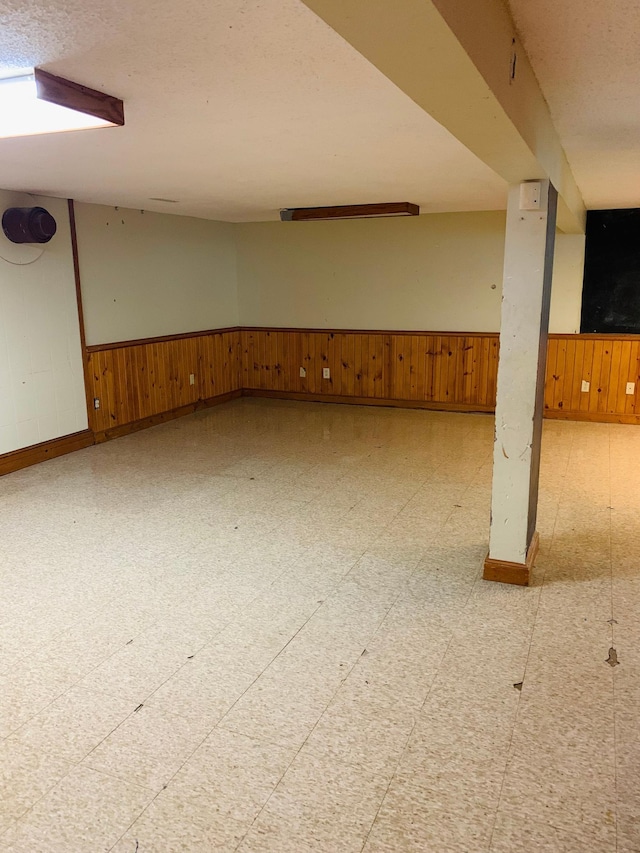 basement featuring a textured ceiling and wood walls