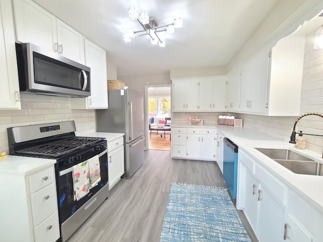 kitchen featuring stainless steel appliances, sink, decorative backsplash, and white cabinets