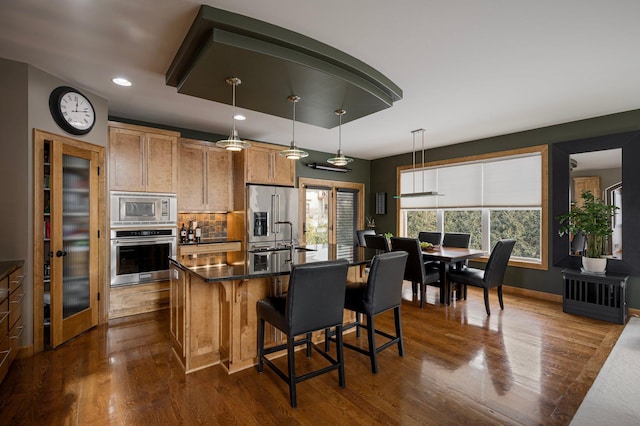 kitchen featuring appliances with stainless steel finishes, dark hardwood / wood-style floors, decorative light fixtures, decorative backsplash, and a center island