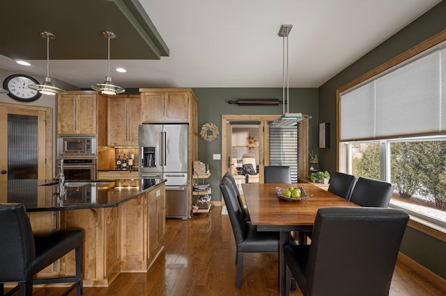 kitchen with a breakfast bar area, stainless steel appliances, a center island, dark hardwood / wood-style flooring, and decorative light fixtures