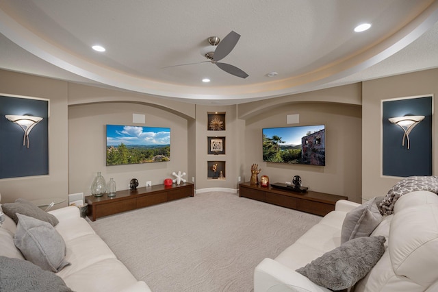 cinema room with ceiling fan, a tray ceiling, and carpet floors