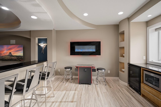 interior space featuring indoor bar, beverage cooler, and light wood-type flooring