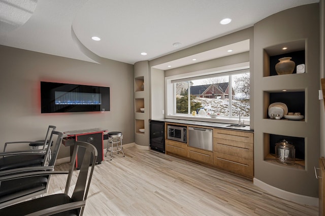 interior space with sink, stainless steel appliances, beverage cooler, and light wood-type flooring