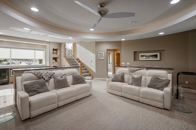 carpeted living room with ceiling fan, a raised ceiling, and a textured ceiling