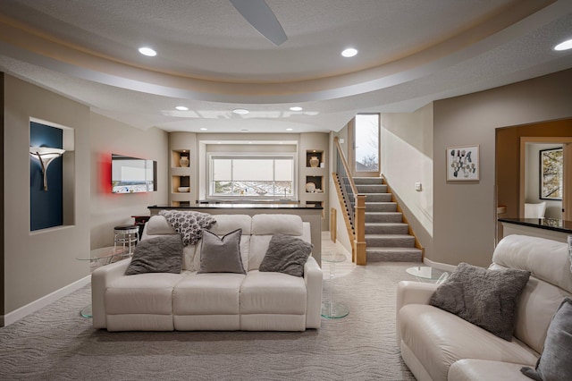 carpeted living room with a tray ceiling and a textured ceiling