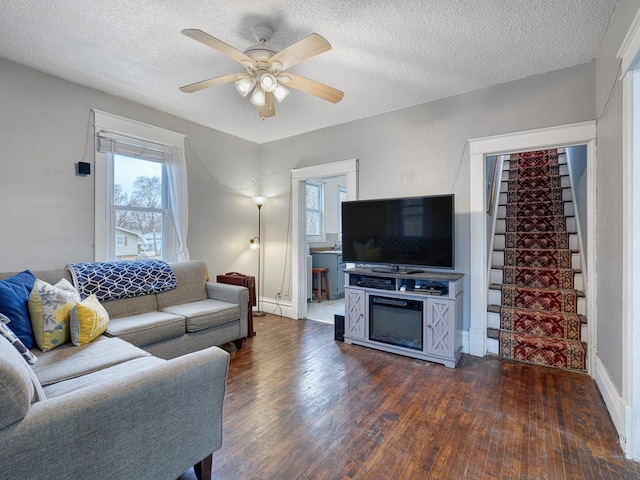 living room featuring dark hardwood / wood-style flooring, a textured ceiling, plenty of natural light, and ceiling fan