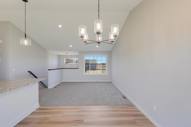 unfurnished dining area featuring an inviting chandelier, lofted ceiling, and light hardwood / wood-style floors