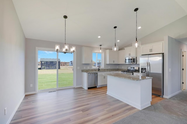 kitchen featuring a kitchen island, appliances with stainless steel finishes, decorative light fixtures, sink, and white cabinets