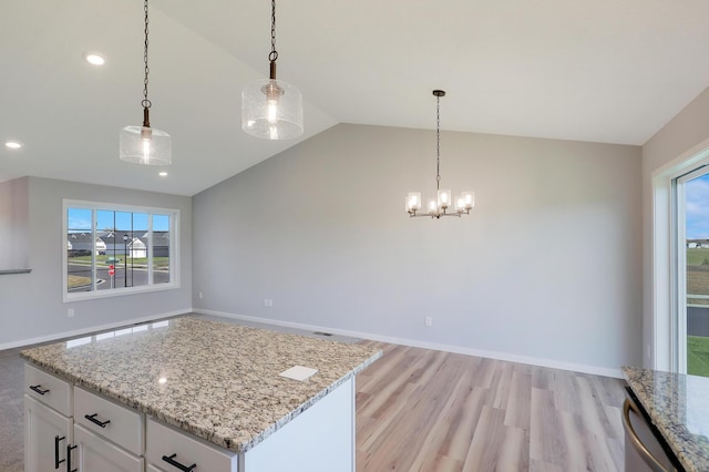 kitchen with hanging light fixtures, vaulted ceiling, a wealth of natural light, and white cabinets