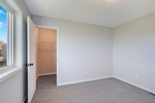 unfurnished bedroom featuring a spacious closet, carpet floors, and a closet