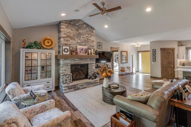 living room with hardwood / wood-style flooring, ceiling fan, lofted ceiling, and a fireplace