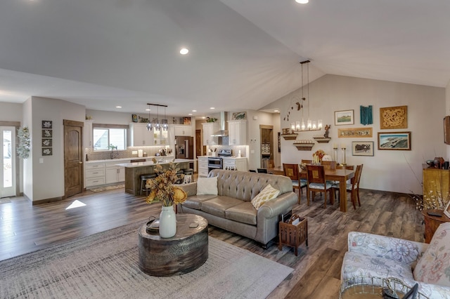 living room with sink, dark hardwood / wood-style floors, a chandelier, and vaulted ceiling