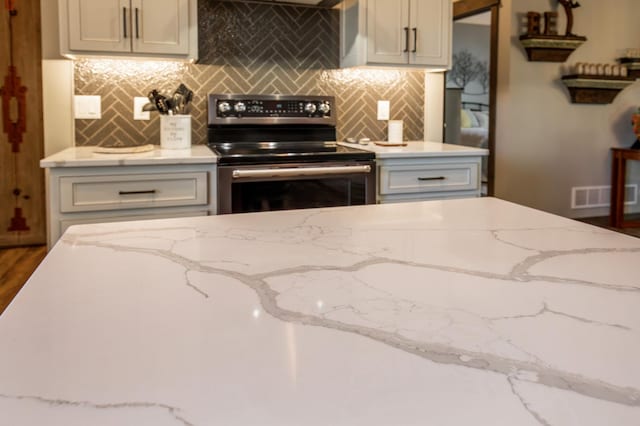 kitchen with light stone counters, wood-type flooring, backsplash, and electric range