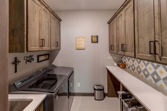 laundry area with cabinets, light tile patterned floors, sink, and washing machine and clothes dryer