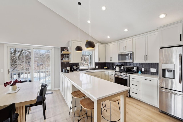 kitchen with pendant lighting, white cabinetry, stainless steel appliances, and sink