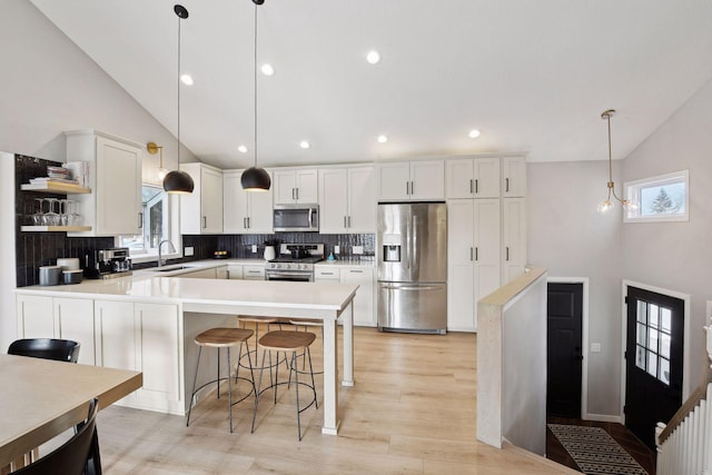 kitchen featuring pendant lighting, stainless steel appliances, sink, and white cabinets