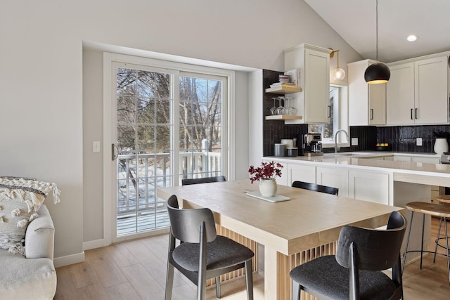 kitchen featuring pendant lighting, backsplash, vaulted ceiling, and white cabinets