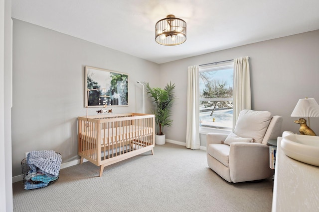 bedroom featuring a nursery area, carpet flooring, and an inviting chandelier